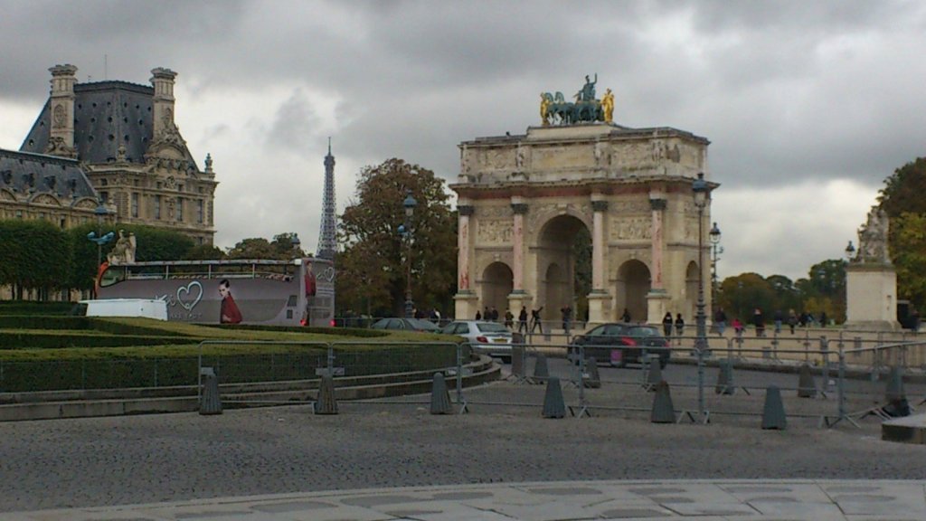 View of the Arc de Triomphe du Carrousel with the Eiffel Tower in the background, set against a cloudy sky.