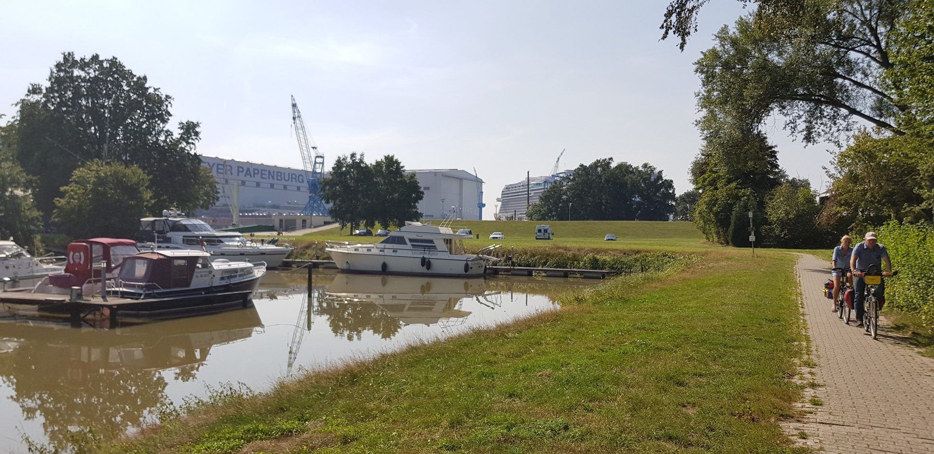 Bepakte fietsers bij de haven van Papenburg met de scheepswerf op de achtergrond